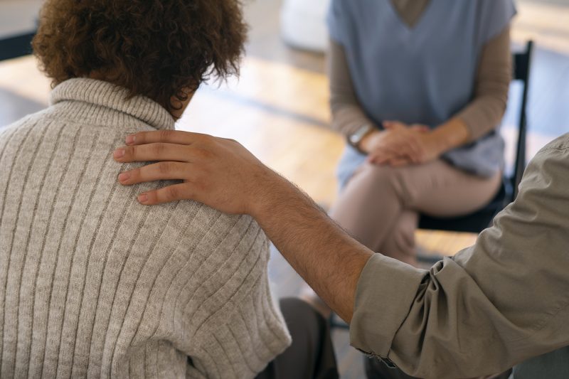 Mężczyzna w trakcie grupowej terapii alkoholowej mówi o swoim doświadczeniu. 